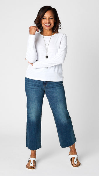 Model wearing cotton blend invisible striped tee in “chalk” white with dark wash cropped wide leg jeans and white sandals.