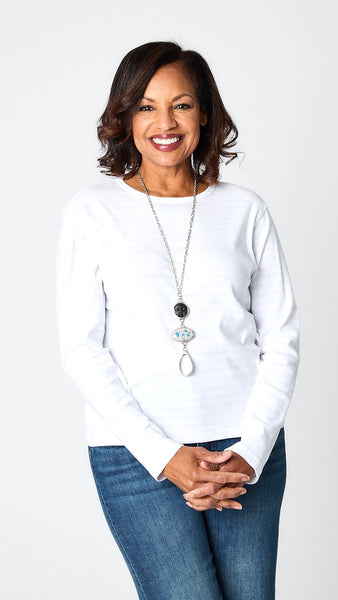 Model wearing cotton blend invisible striped tee in “chalk” white with three drop pendant necklace, dark wash cropped wide leg jeans, and white sandals.