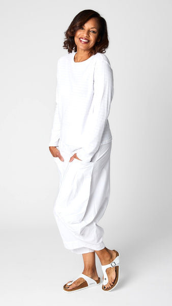 Model wearing cotton blend invisible striped tee in “chalk” white with white tencel/cotton cropped double pocket lantern pants and white sandals.
