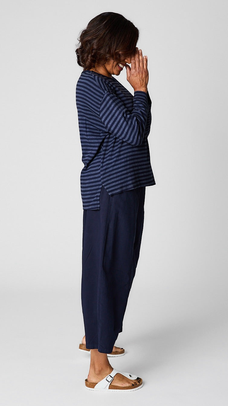 Model wearing "indigo" striped relaxed long sleeve tee, "indigo" cropped pant with one pocket, and white leather sandals.
