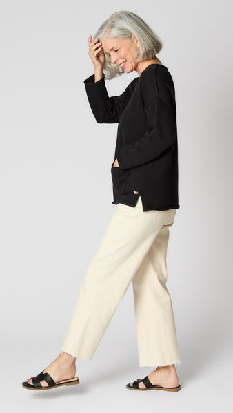 Model wearing black boatneck sweater with patch pockets, and ecru cropped wide-leg jeans.