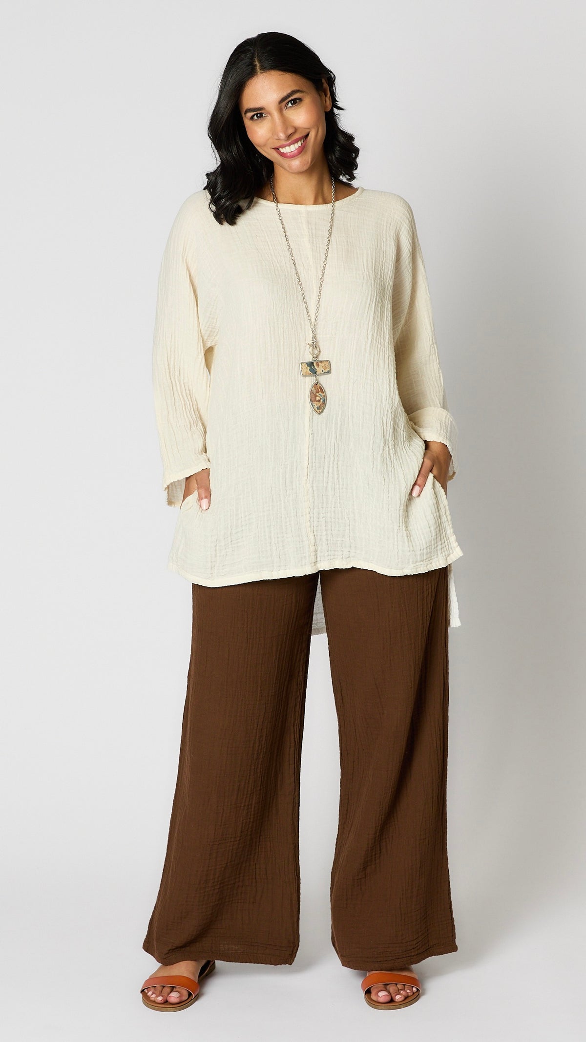 Model wearing chocolate crinkle cotton palazzo pants, cream oversized hi-lo double cotton tunic, and brown leather sandals.
