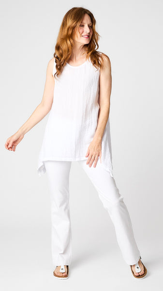 Model wearing chalk long tunic tank with sweeping swing hemline, white bootcut jeans, and white sandals.