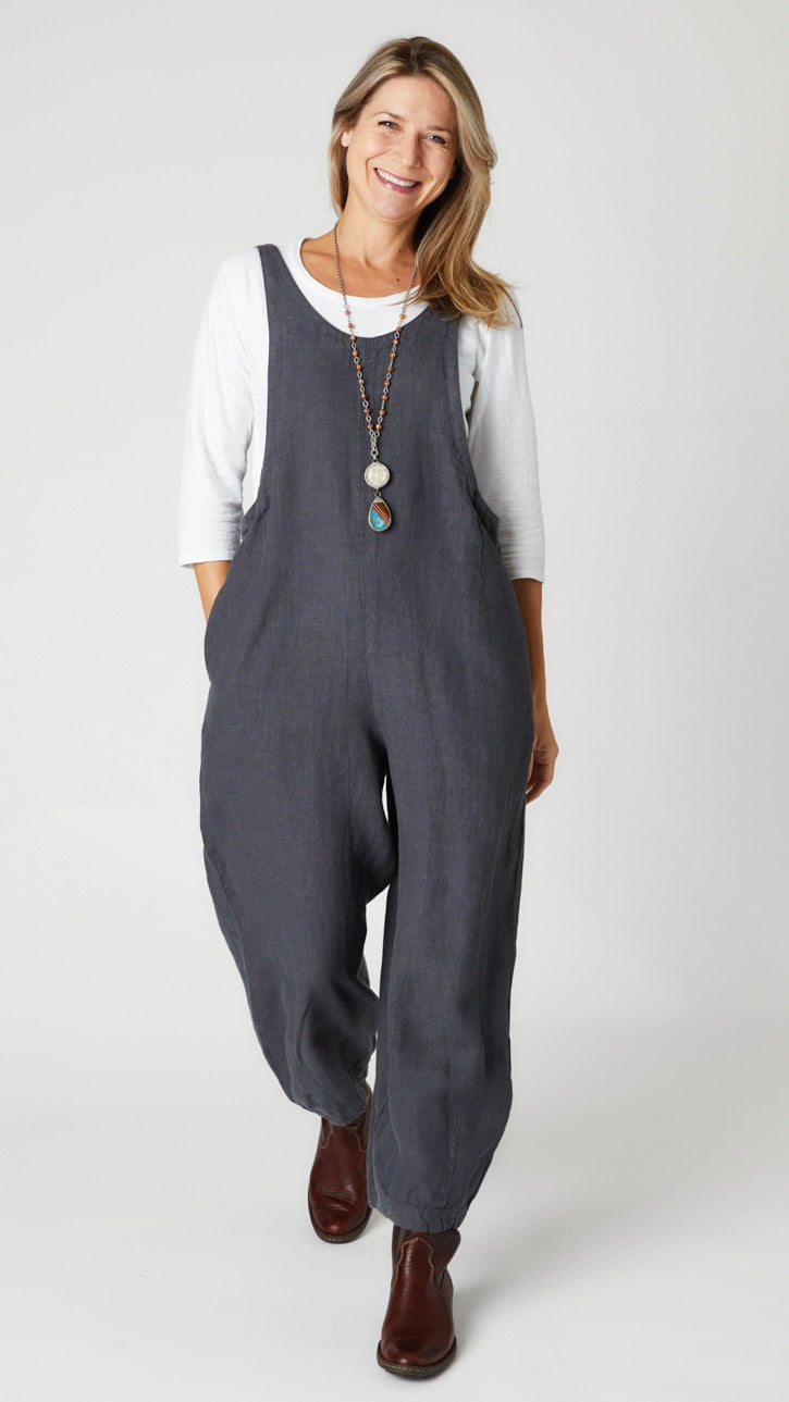 Model wearing "iron" linen overall jumpsuit with wide cropped dart leg, white 3/4 sleeve bias cut tee, and brown leather boots.