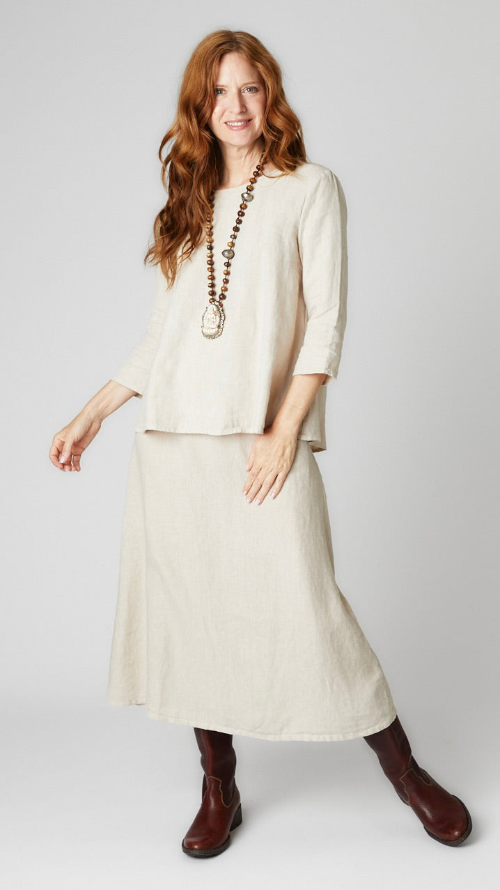 Model wearing natural linen A-line top with 3/4 sleeves, natural linen A-line midi skirt, and brown leather boots.