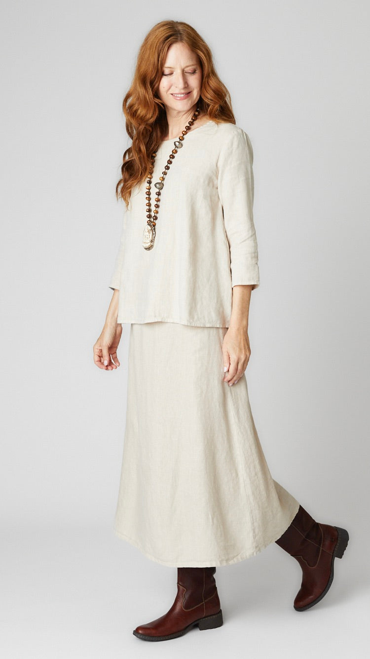Model wearing natural linen A-line top with 3/4 sleeves, natural linen A-line midi skirt, and brown leather boots.