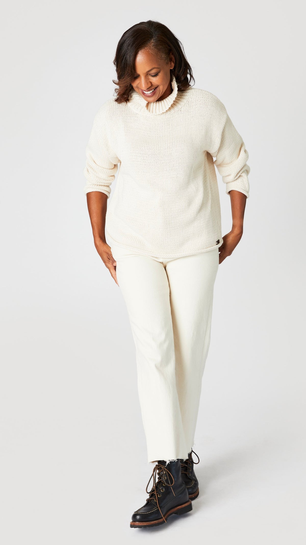 Model wearing cream cotton sweater with turtleneck, ecru cropped wide leg jeans, and black leather boots.