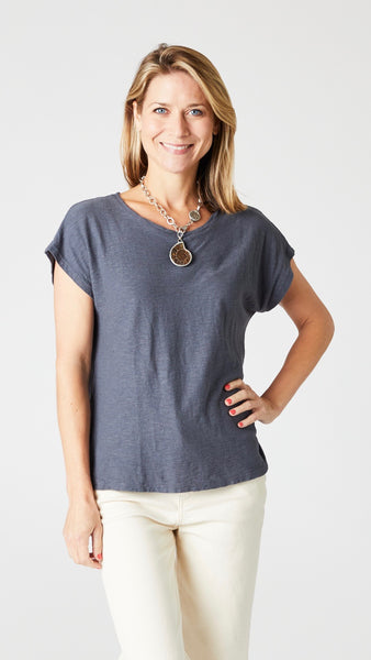 Model wearing anthracite cotton-linen jersey top with cropped sleeves, boatneck, and boxy silhouette with ecru denim jeans.