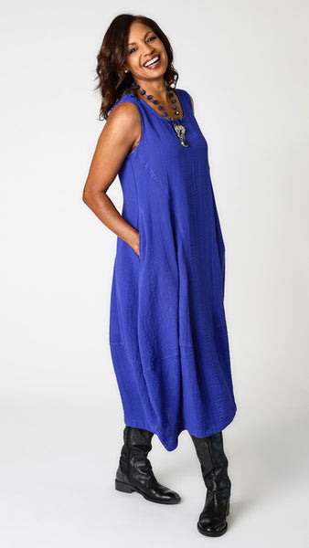 Model wearing "galaxy" sleeveless rayon dress with tulip hemline and round neck, lapis beaded necklace with silver jaguar pendant, and black leather boots.