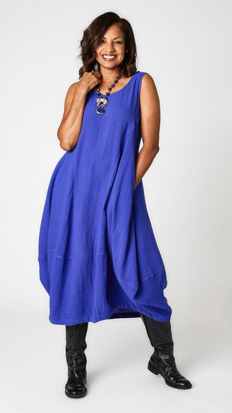 Model wearing "galaxy" sleeveless rayon dress with tulip hemline and round neck, lapis beaded necklace with silver jaguar pendant, and black leather boots.