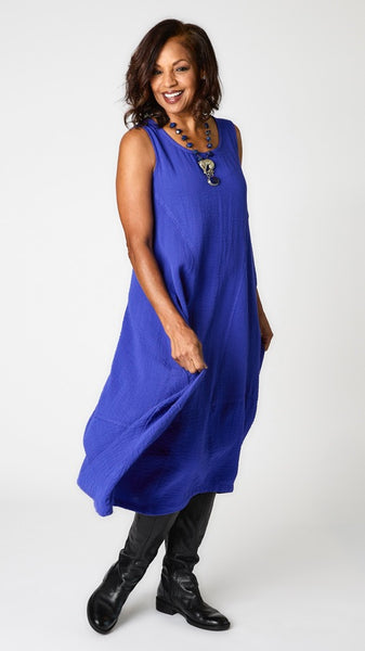 Model wearing "galaxy" sleeveless rayon dress with tulip hemline and round neck, lapis beaded necklace with silver jaguar pendant, and black leather boots.