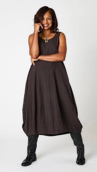 Model wearing "mineral" sleeveless rayon dress with tulip hemline and round neck, and black leather boots.