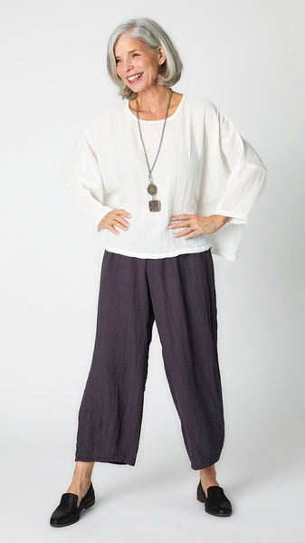 Model wearing white cropped one size top in travel weight rayon with anthracite cropped pants with ankle darts and black leather loafers.
