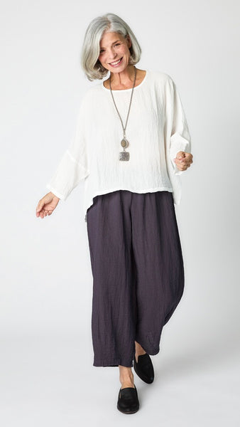 Model wearing white cropped one size top in travel weight rayon with anthracite cropped pants with ankle darts and black leather loafers.