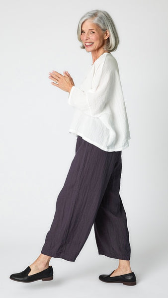 Model wearing white cropped one size top in travel weight rayon with anthracite cropped pants with ankle darts and black leather loafers.