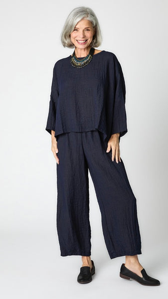 Model wearing cropped ink rayon top with high round neckline, dropped shoulders and ¾ sleeves, ink cropped dart pants, and black loafers.