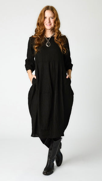 Model wearing black rayon dress with scoop neck, 3/4 sleeves, and tulip hemline, with black leather boots.