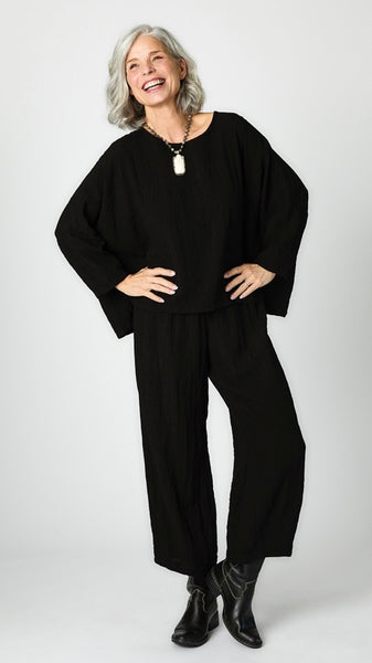 Model wearing black cropped one size top in travel weight rayon with black cropped pants with ankle darts and black leather boots.