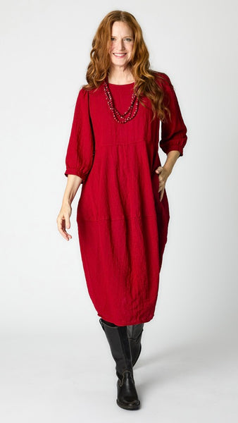 Model wearing cardinal red rayon dress with scoop neck, 3/4 sleeves, and tulip hemline, with black leather boots.
