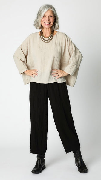 Model wearing natural cropped one size top in travel weight rayon with black cropped pants with ankle darts and black leather boots.