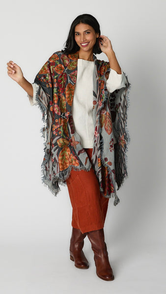Model wearing gray and orange floral ruana over cream resort top and aperitivo casbah pants with brown leather boots.