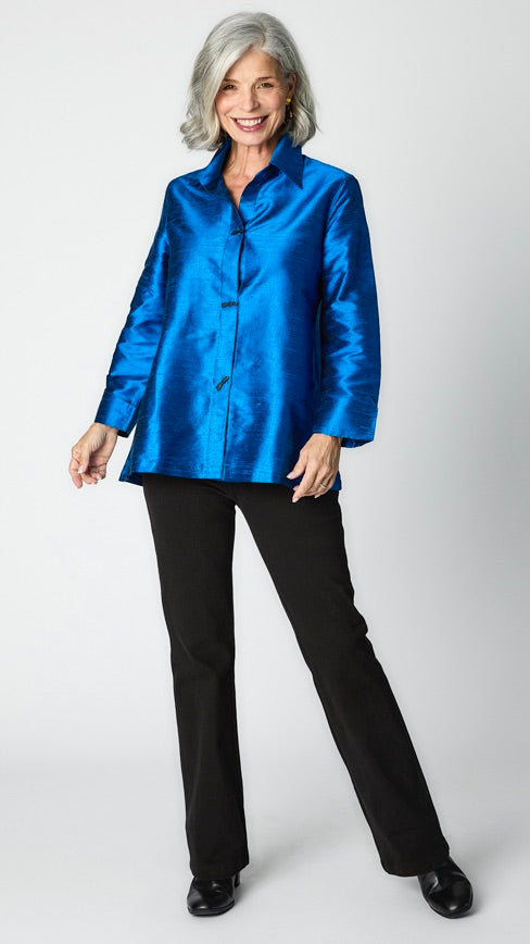 Model wearing royal raw silk button-up blouse with black horn buttons and 3/4 sleeves, black wideleg trousers, and black leather heeled boot.