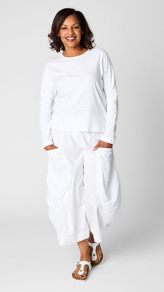 Model wearing cotton blend invisible striped tee in “chalk” white with white tencel/cotton cropped double pocket lantern pants and white sandals.