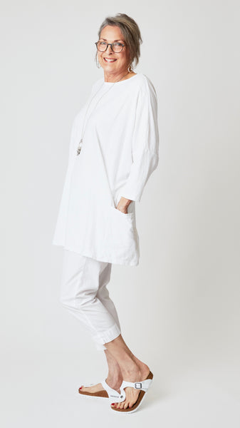 Model wearing oversized white cotton-linen jersey tunic with white cropped, tapered poplin cotton pant and white sandals.