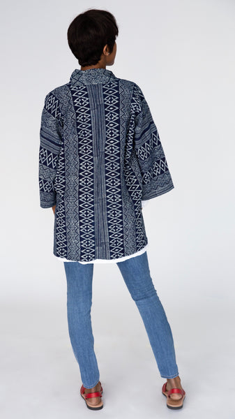 Rear view of model wearing indigo block print cotton kimono, white t-shirt, midwash denim leggings, and red slingback flats.