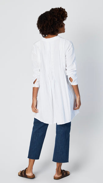 Rearview of white cotton twill tunic shows garment's rear pleating. 