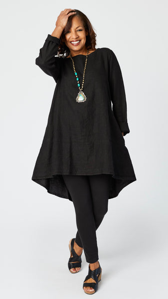 Model wearing black high-low linen tunic with long sleeves, silver beaded turquoise pendant necklace,  black cotton leggings, and black leather sandals.