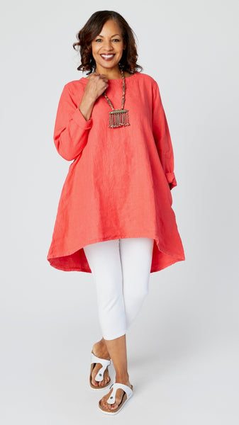 Model wearing coral red high-low linen tunic, white capri leggings, and white sandals. 