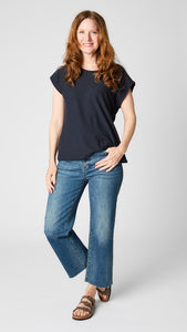 Model wearing ink cotton-linen jersey top with cropped sleeves, boatneck, and boxy silhouette with dark vintage wash cropped wideleg jeans and brown sandals.