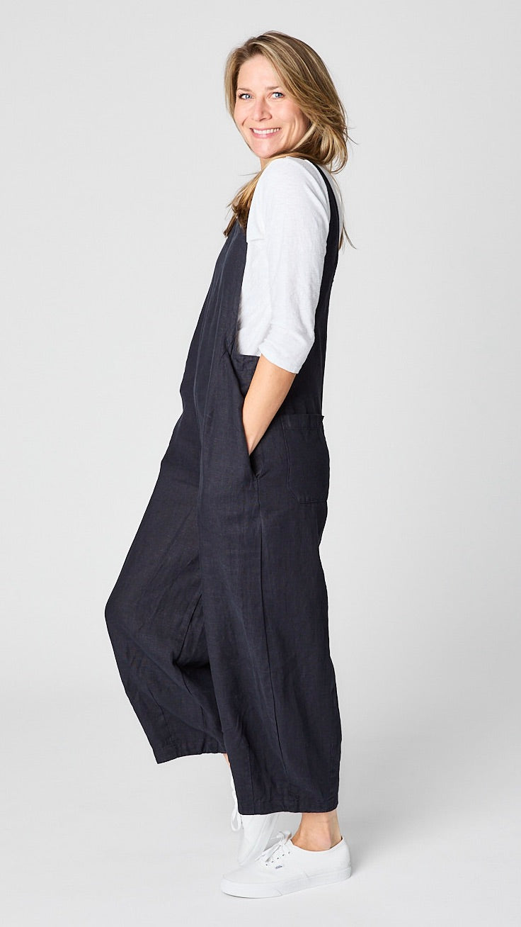 Model wearing "ink" linen overall jumpsuit with wide cropped dart leg, white 3/4 sleeve bias cut tee, and white sneakers.