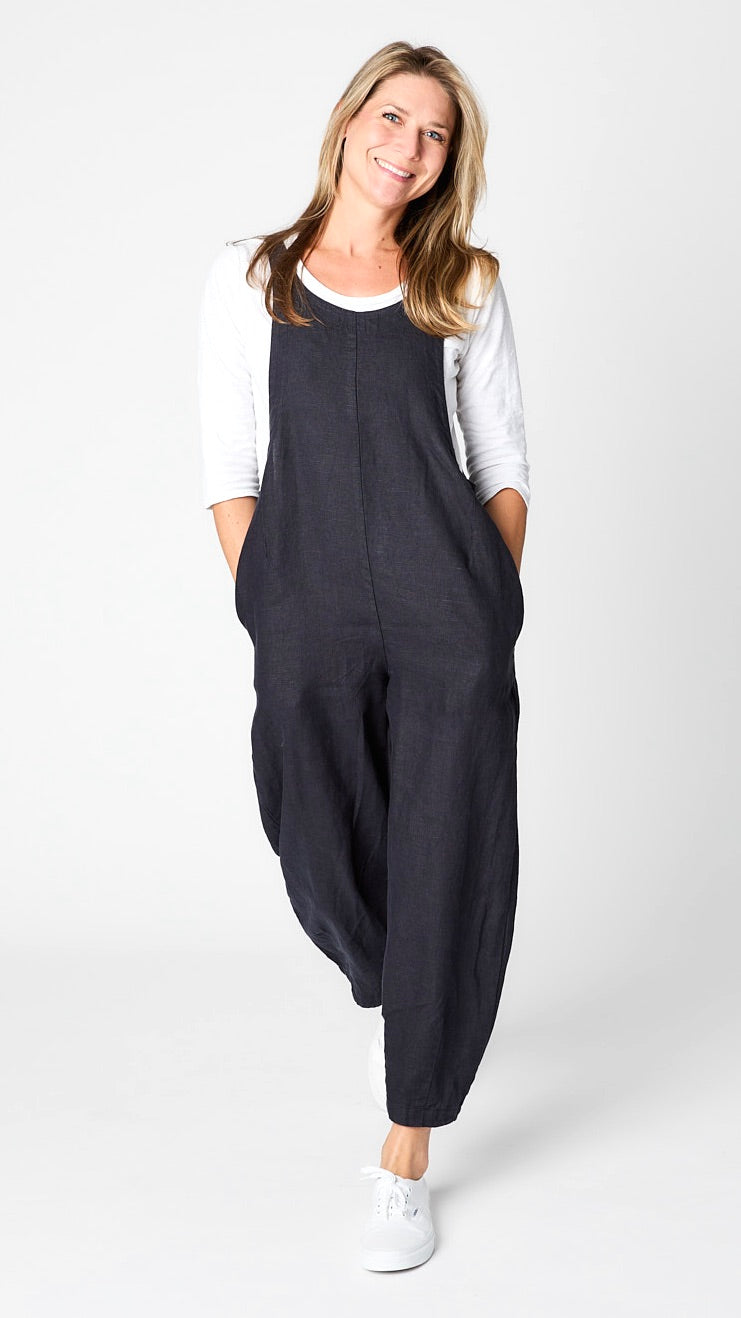 Model wearing "ink" linen overall jumpsuit with wide cropped dart leg, white 3/4 sleeve bias cut tee, and white sneakers.