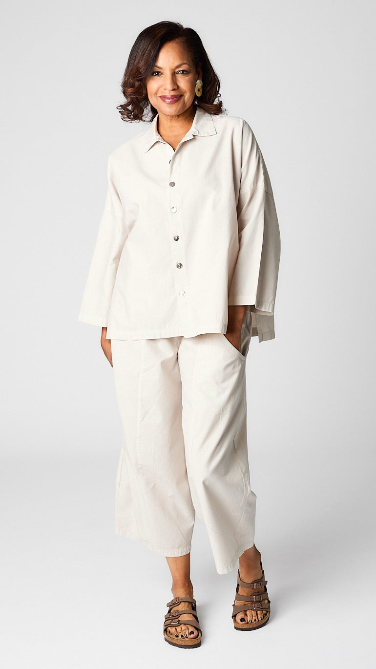Model wearing cloud button-up top with relaxed hemline and 3/4 sleeves over cloud cropped one pocket pants and brown sandals.