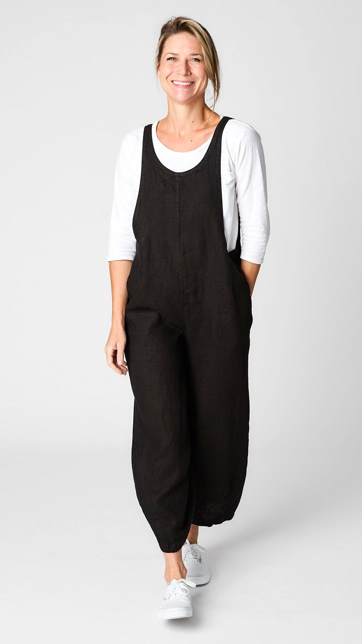Model wearing black linen overall jumpsuit with wide cropped dart leg, white 3/4 sleeve bias cut tee, and white sneakers.