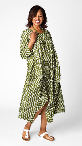 Model wearing acorn green & white dress with 3/4 sleeves, variable hemline, and gathered pleats.