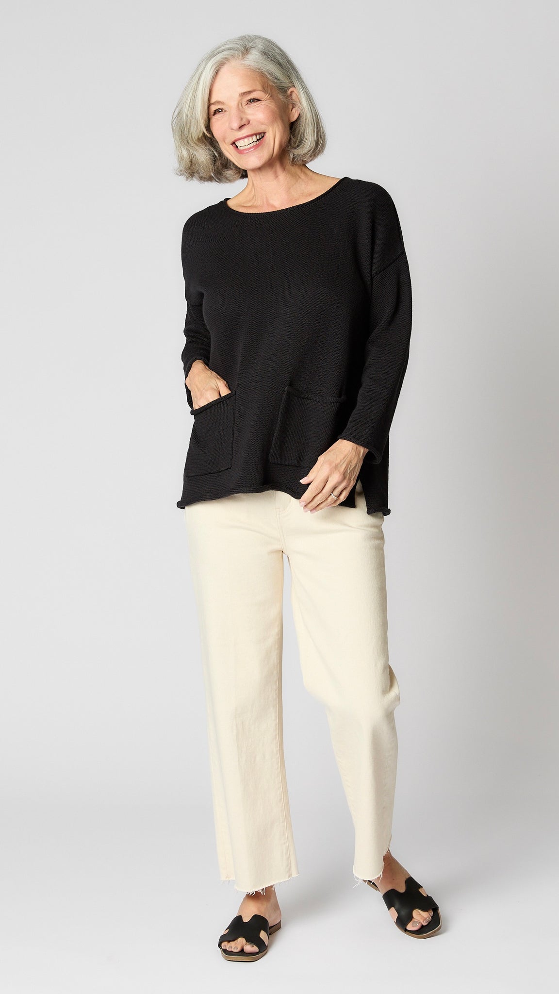 Model wearing black boatneck sweater with patch pockets, and ecru cropped wide-leg jeans.