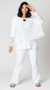 Model wearing white cotton handknit sweater overlay, white cotton-linen blend tunic, and white bootcut jeans.