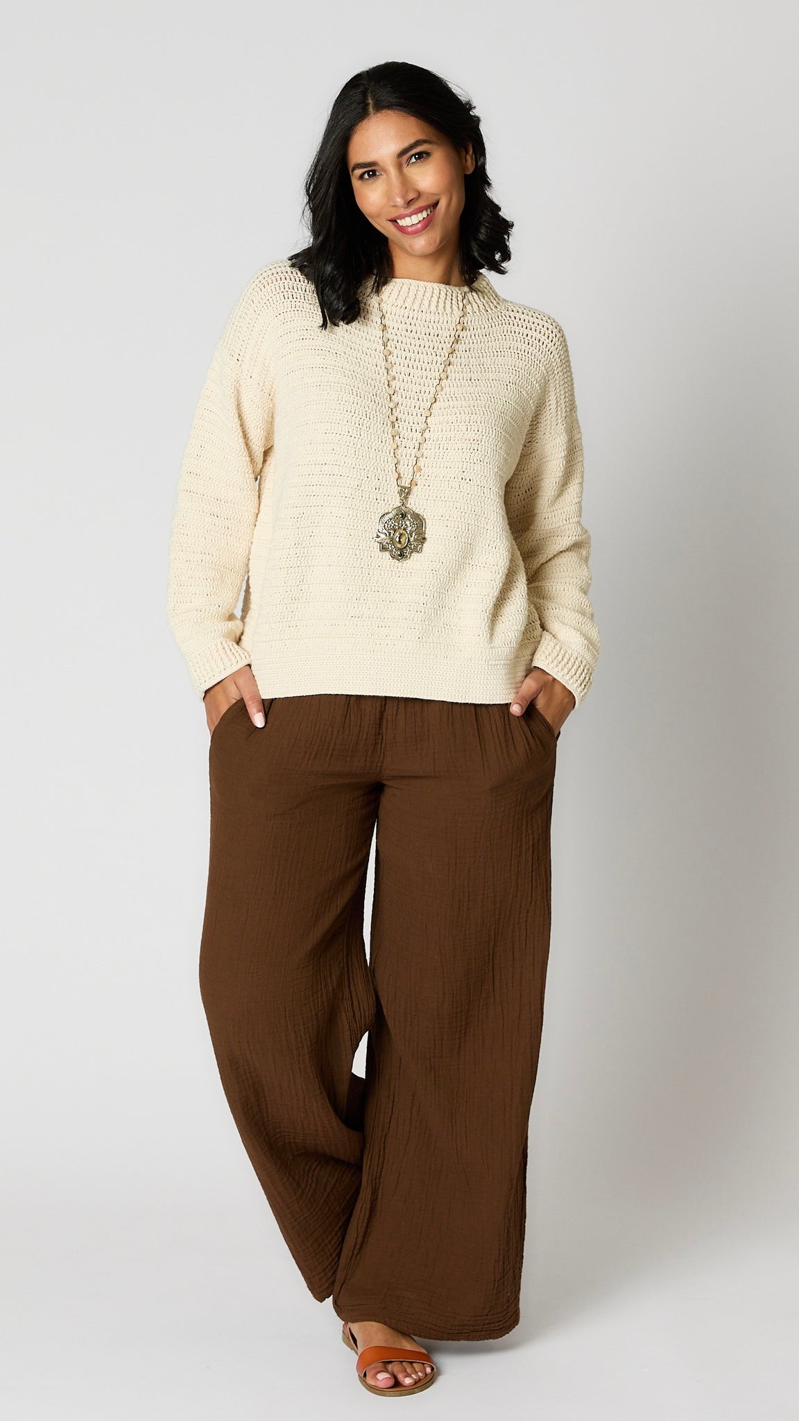 Model wearing natural cotton cropped crochet crew sweater, chocolate crinkle cotton palazzo pant, and brown leather sandals.