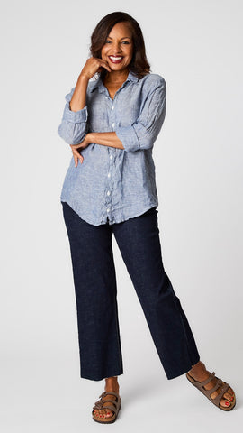 Model wearing blue chambray relaxed fit button up shirt in handkerchief linen, dark wash cropped wideleg jeans, and brown sandals. 