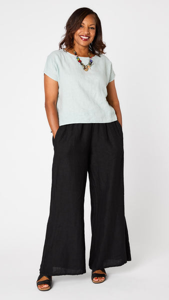 Model wearing "moonlight" short sleeve linen top with hi-lo hemline, black wideleg pant, colorful charm necklace, and black sandals. 