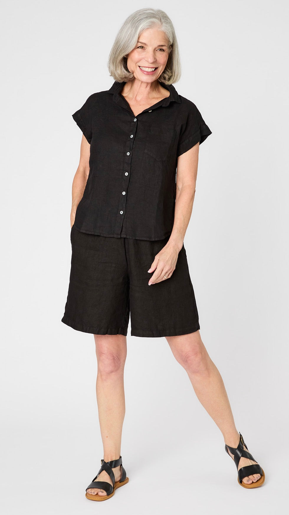 Model wearing black linen short sleeve linen button-up top, black linen shorts, and black leather sandals.