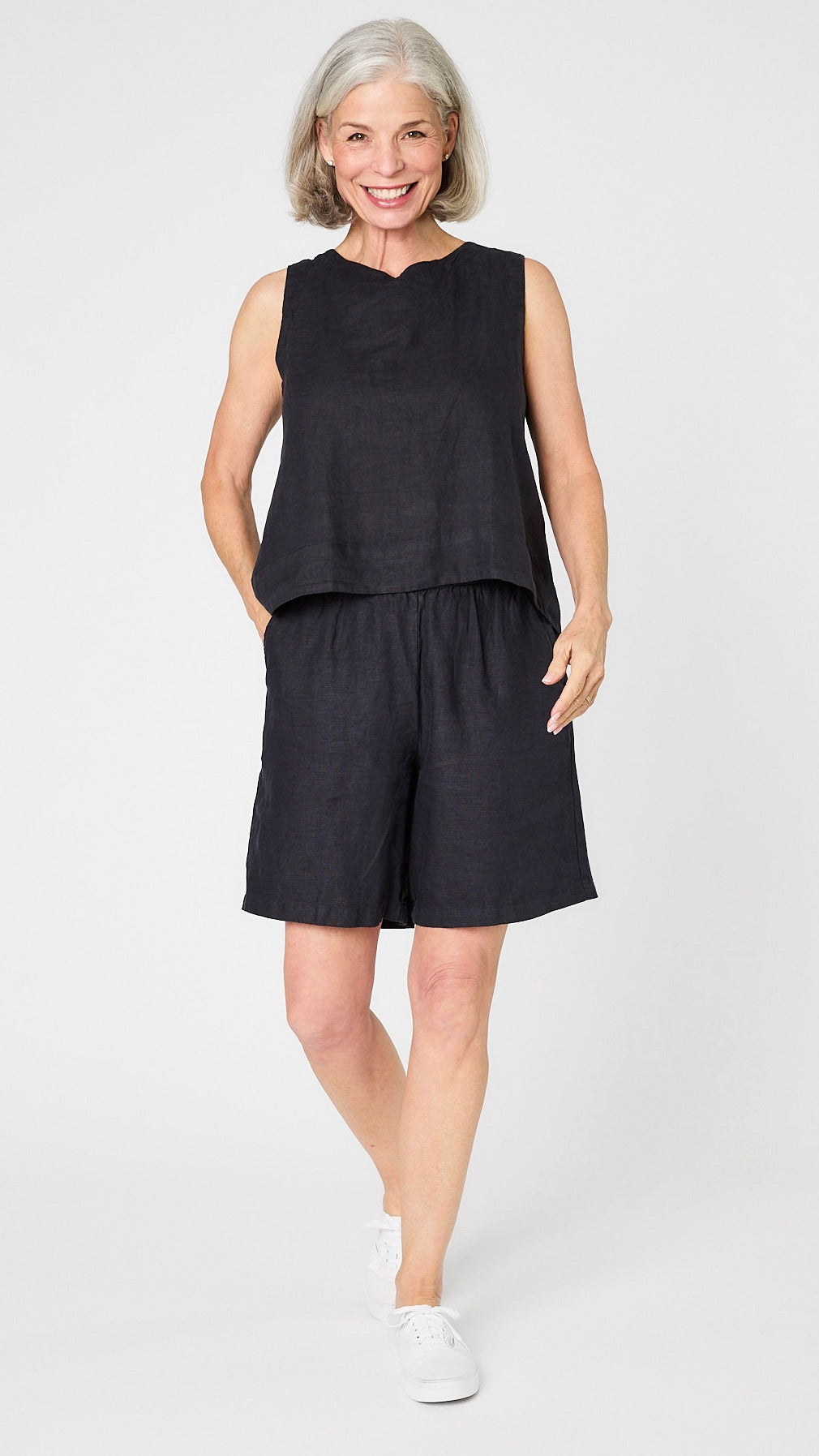 Model wearing ink linen sleeveless tank with hi-lo silhouette, ink linen knee length shorts, and white sneakers.
