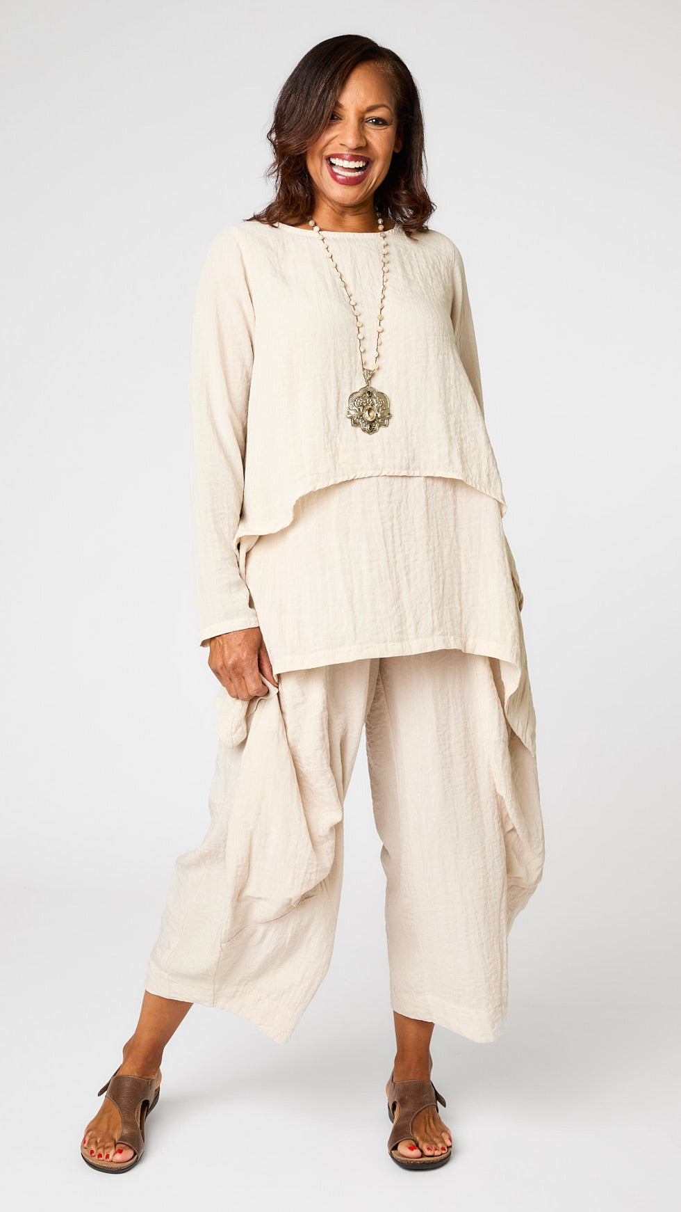 Model wearing cloud long sleeve cropped top with A-line silhouette, cloud layer tank, and cloud double pocket pant with brown leather sandal.