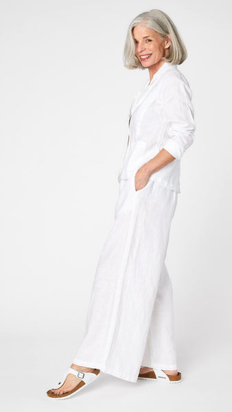 Model wearing white linen blazer over white, high waisted, wide leg linen pants with white sandals. 
