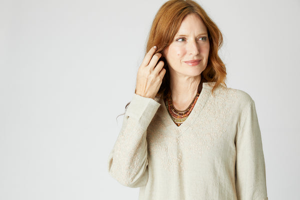 Close-up of model wearing natural linen tunic with Nehru neckline, embroidered sleeves and yoke displays embroidered details. 