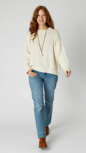 Model wearing cream crochet cotton sweater, straight-leg, high-waisted mid-wash jean, brown suede boots and  bone crescent moon pendant necklace. 