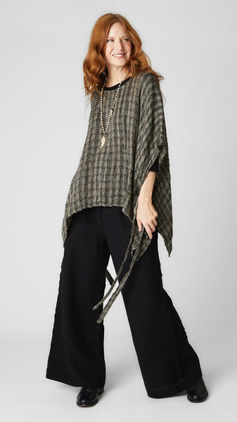 Model wearing black crinkle cotton palazzo pant, black loosely woven linen topper, and black leather boots.